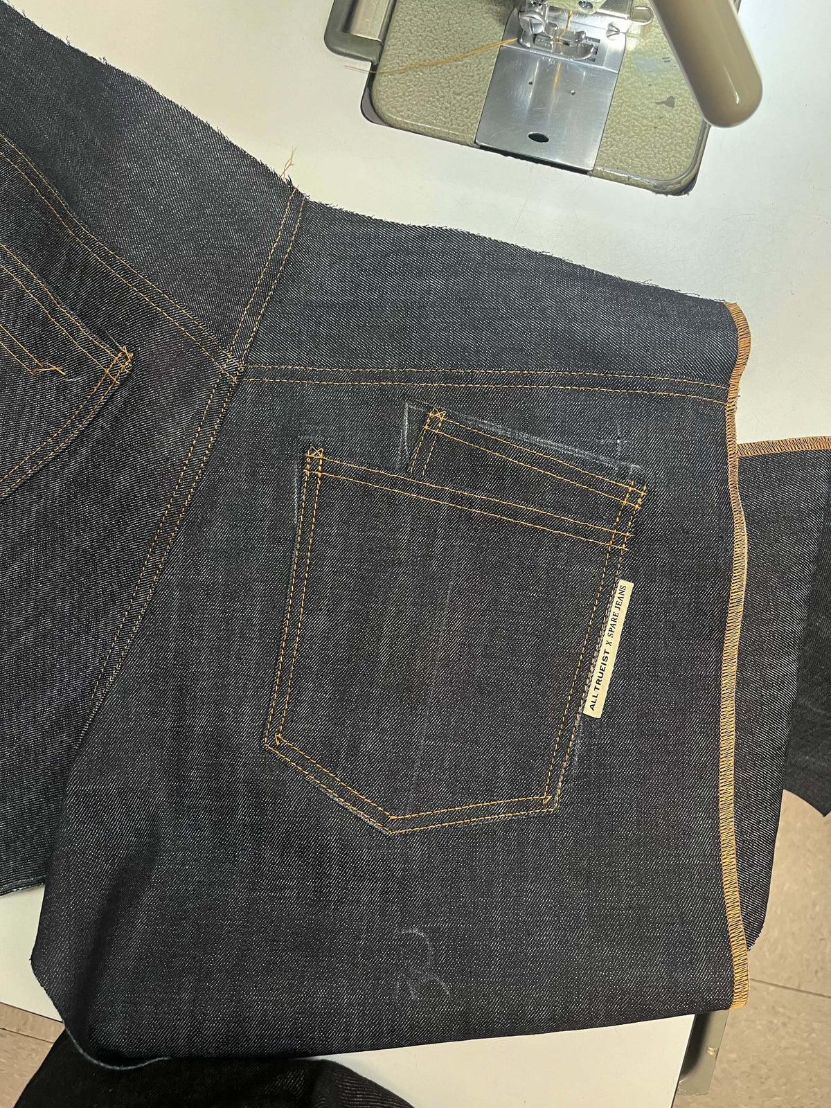 Denim panels and stitching beside a sewing machine