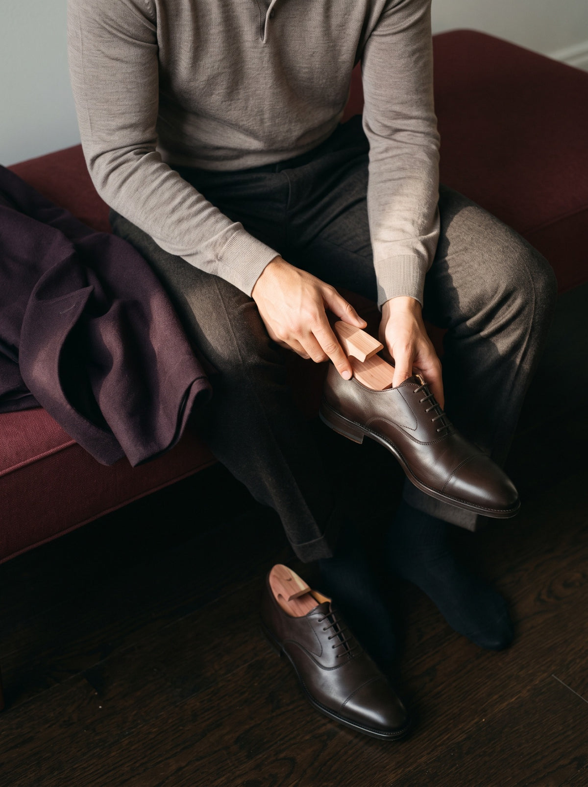 A man placing a cedar shoe tree inside a dark leather shoe