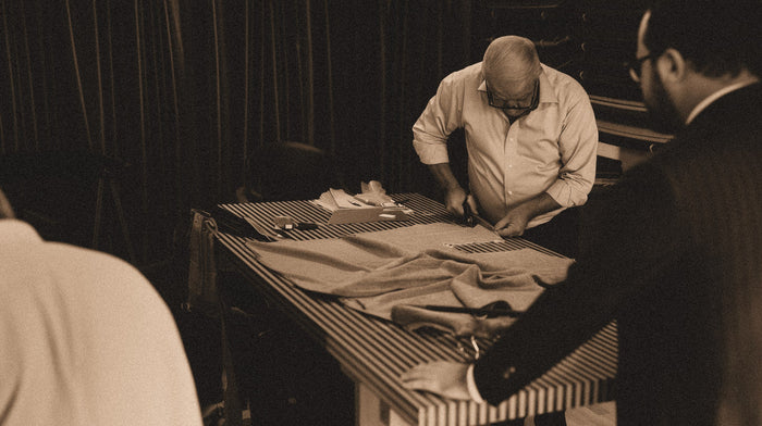 A skilled master tailor carefully cutting fabric by hand in a traditional atelier, showcasing the meticulous craft and precision behind each bespoke garment.
