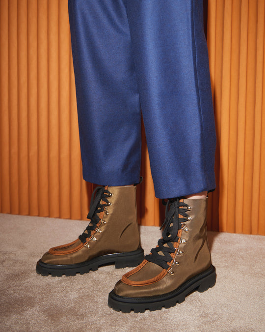AERA AMALIA dark khaki lace-up boots with lug soles, worn with blue wide-leg trousers.
