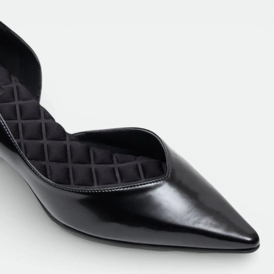 Black pointed-toe flat shoe with quilted cushioned insole on white background