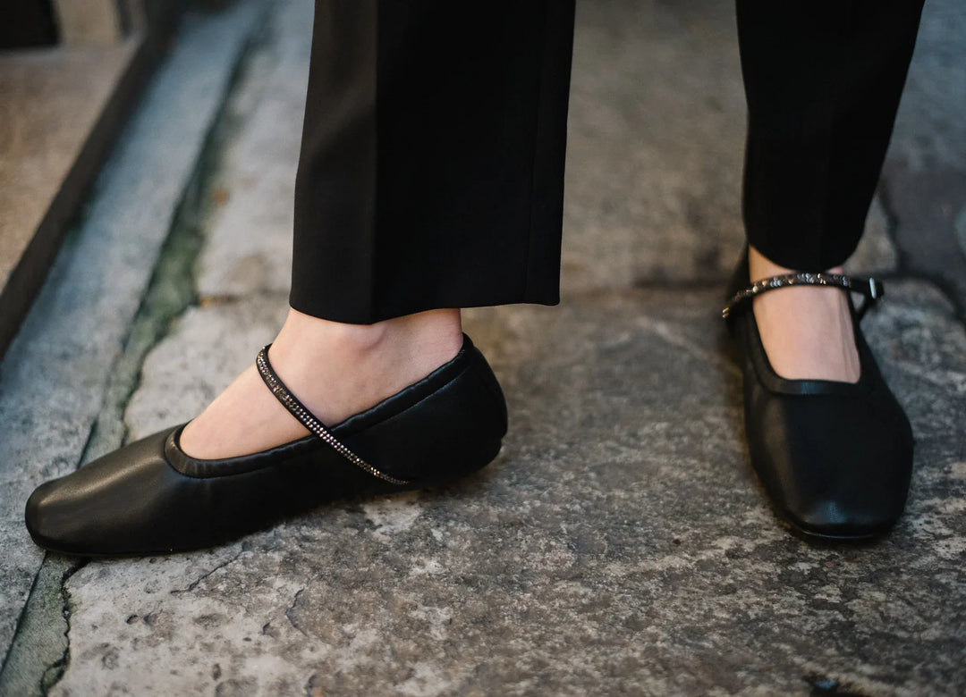 Woman wearing AERA Aurora black Nappa Crystal Mary Jane flats, vegan and sustainable shoes, on stone pavement.