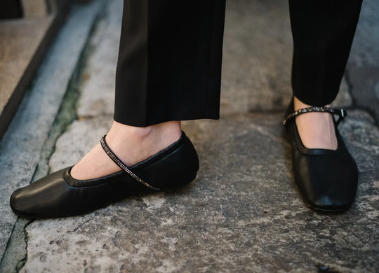 Woman wearing AERA Aurora black Nappa Crystal Mary Jane flats, vegan and sustainable shoes, on stone pavement.