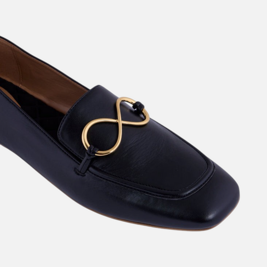 AERA ELLA black nappa-effect loafer, close-up of the gold-tone infinity hardware and rounded toe.
