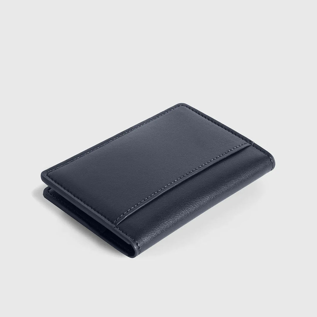 Compact navy blue leather wallet with minimalist design on a light background