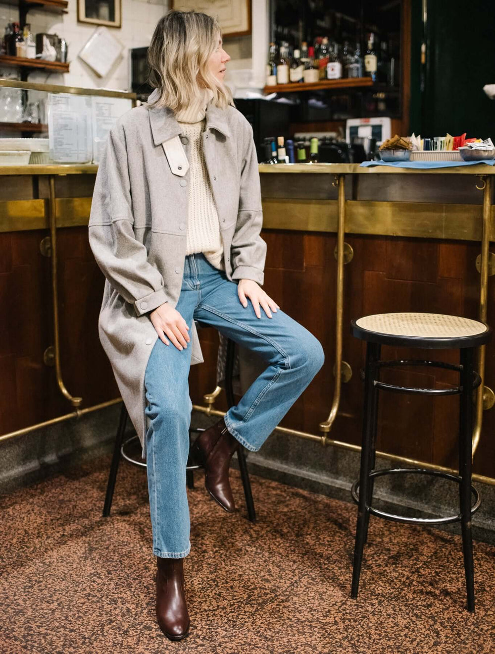 Woman wearing STEFFY Brown Capretto Ankle Boots, sitting at a bar in a casual outfit.
