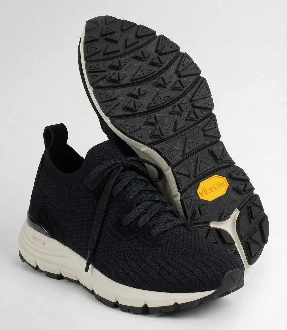 Black knit sneaker with white sole and textured black Vibram outsole, front and bottom view