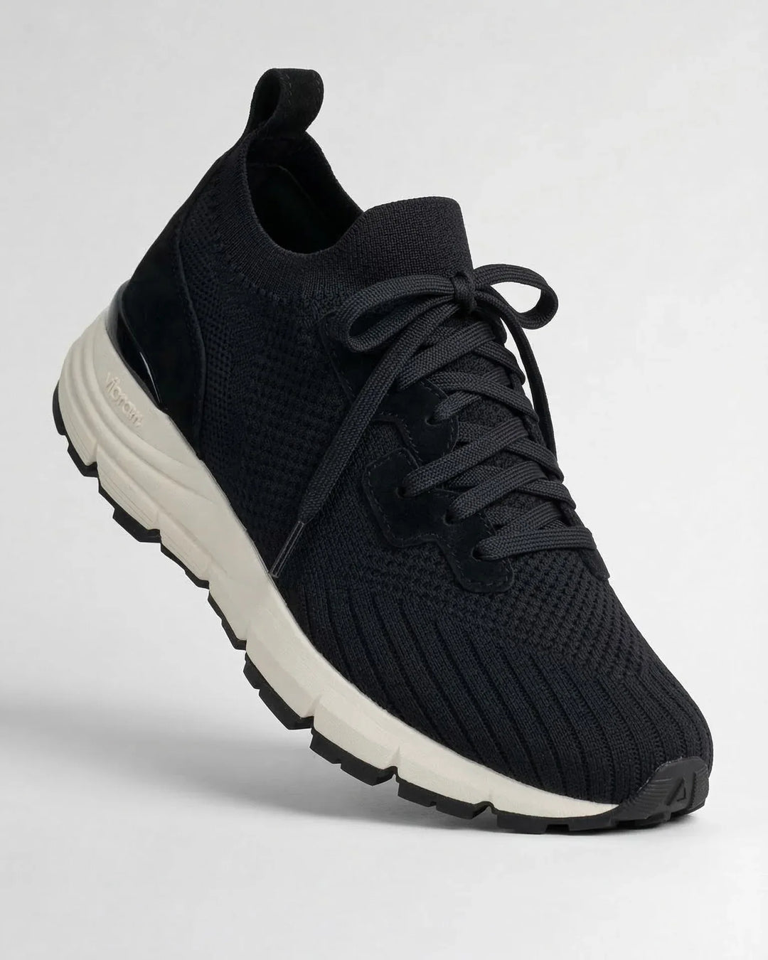 Black knit sneaker with suede accents and white Vibram sole, modern minimalist design