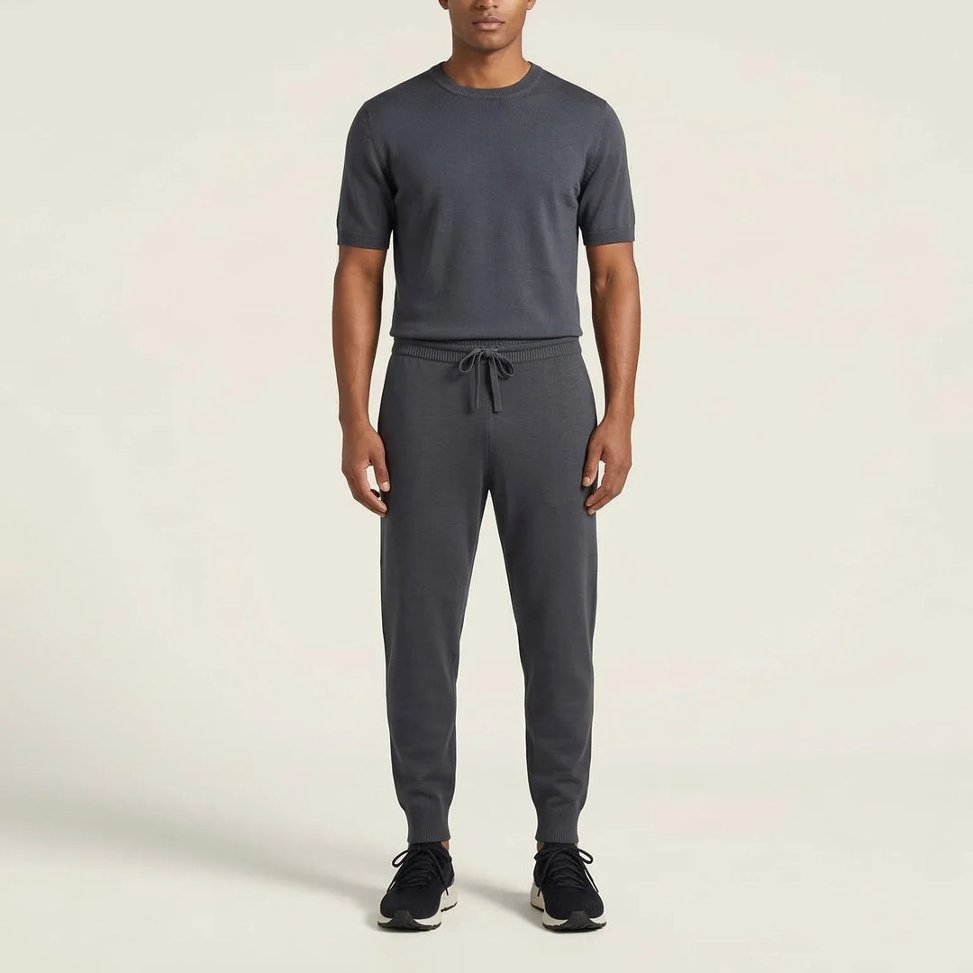 Man wearing charcoal grey short-sleeve knit shirt and jogger pants set with black sneakers