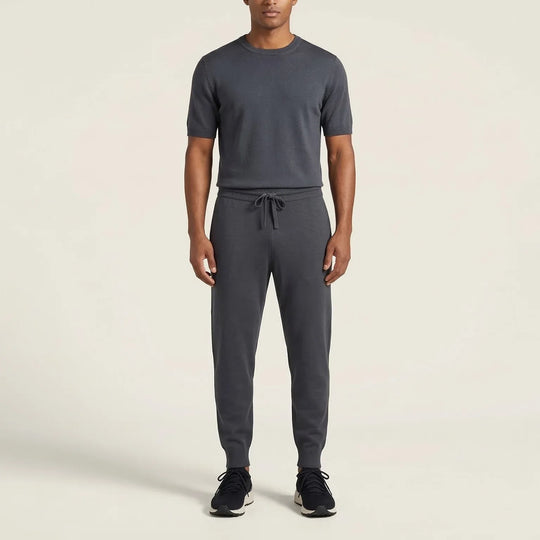 Man wearing charcoal grey short-sleeve knit shirt and jogger pants set with black sneakers