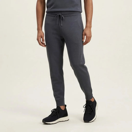 Man wearing dark grey knit jogger pants with drawstring waist and ribbed cuffs