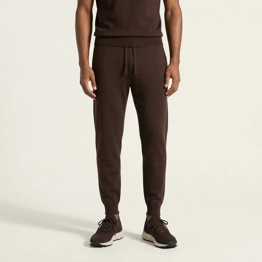 Men's brown knit jogger pants with drawstring waist and ribbed cuffs, paired with sneakers