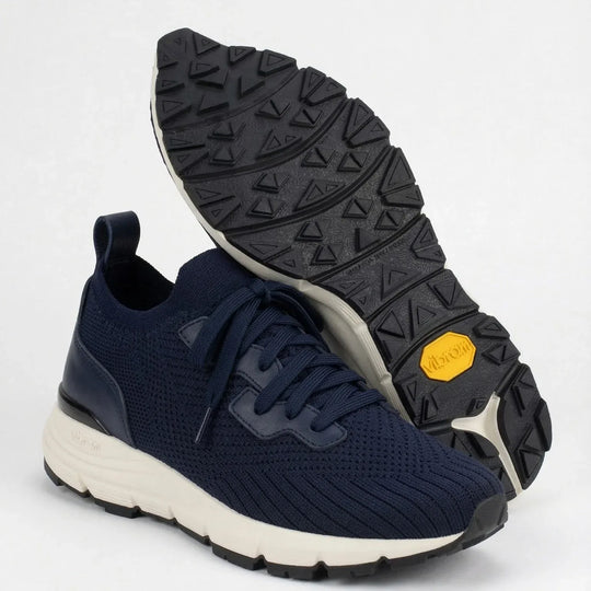 Navy blue knit sneakers with white sole and black textured outsole displayed on white background