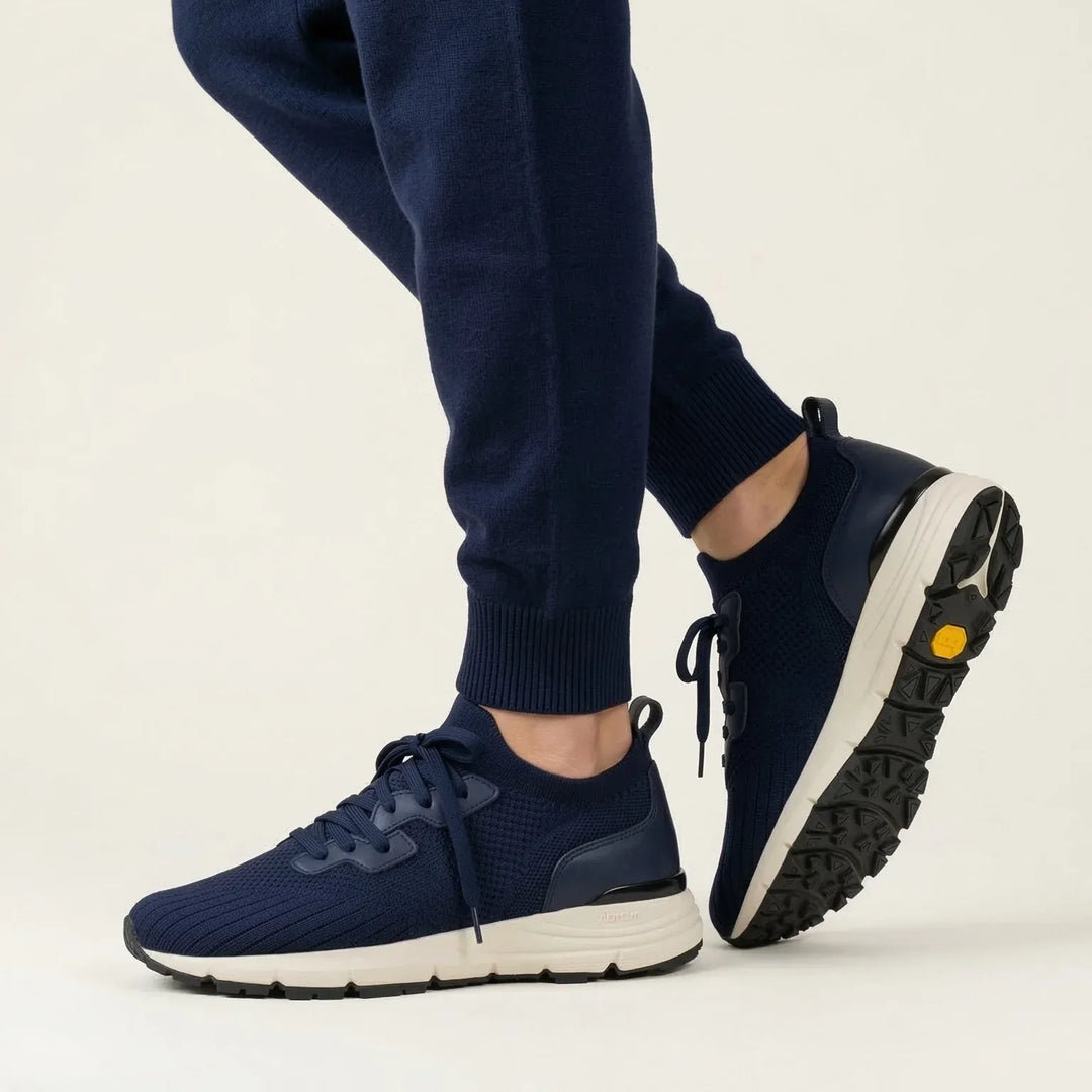 Navy blue knit lace-up sneakers with white soles worn with matching joggers
