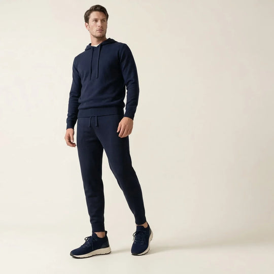 Man wearing navy blue hooded sweatshirt and matching joggers with navy sneakers