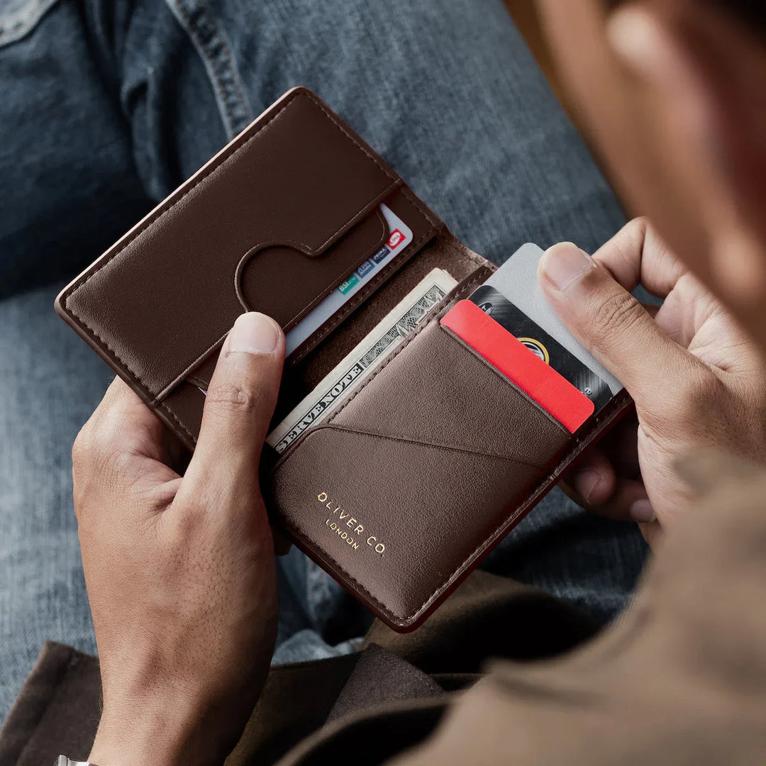 Man holding an open brown compact wallet with cards and cash slot, premium leather.