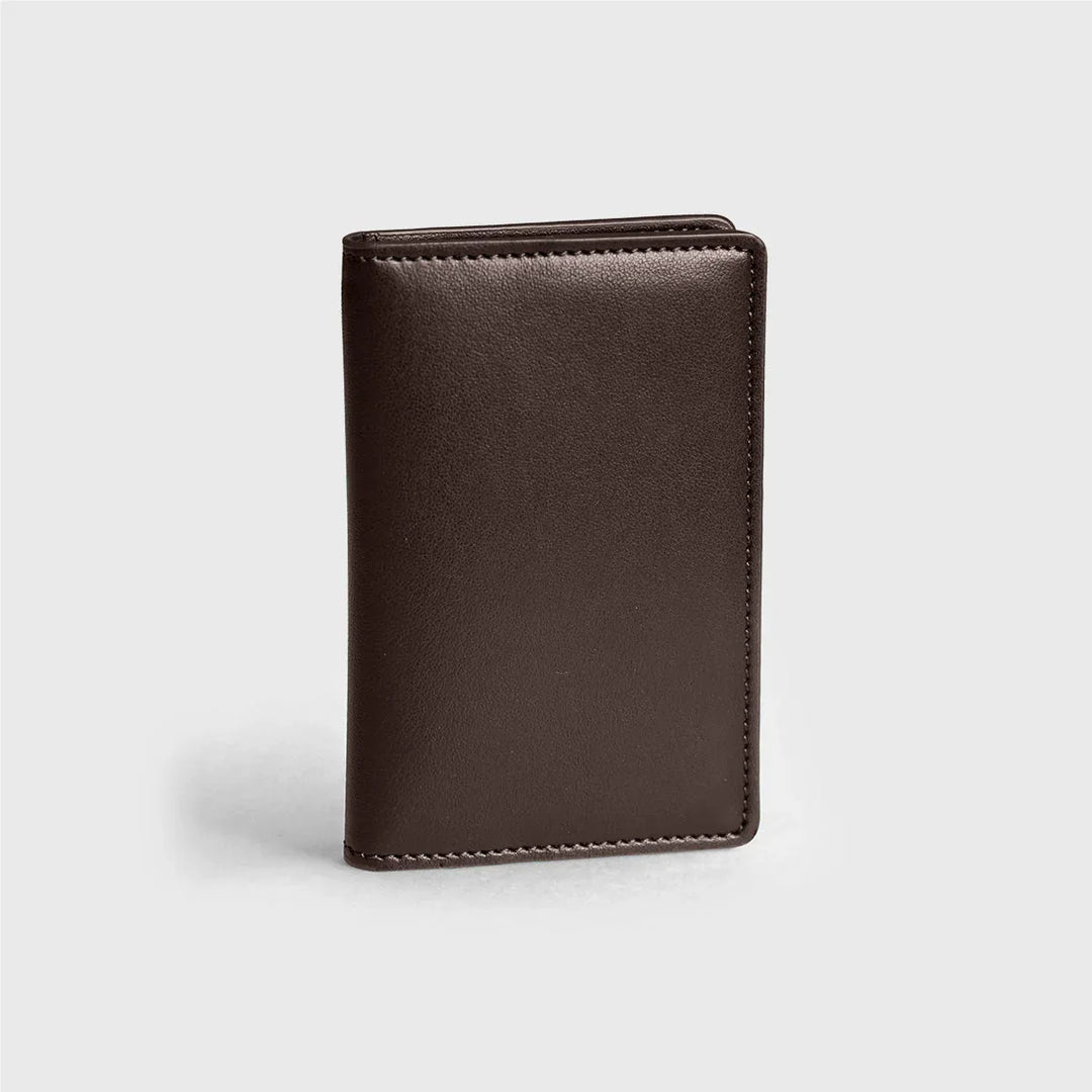 Walnut brown compact leather wallet standing on light background