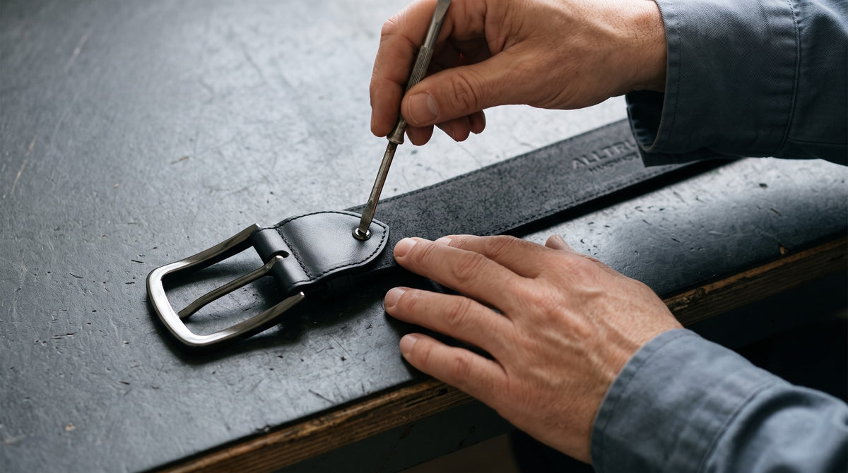 Hands securing the buckle attachment of a black belt at a workbench.
