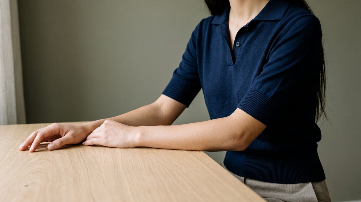 Woman seated at an oak table wearing a navy cotton knit polo.
