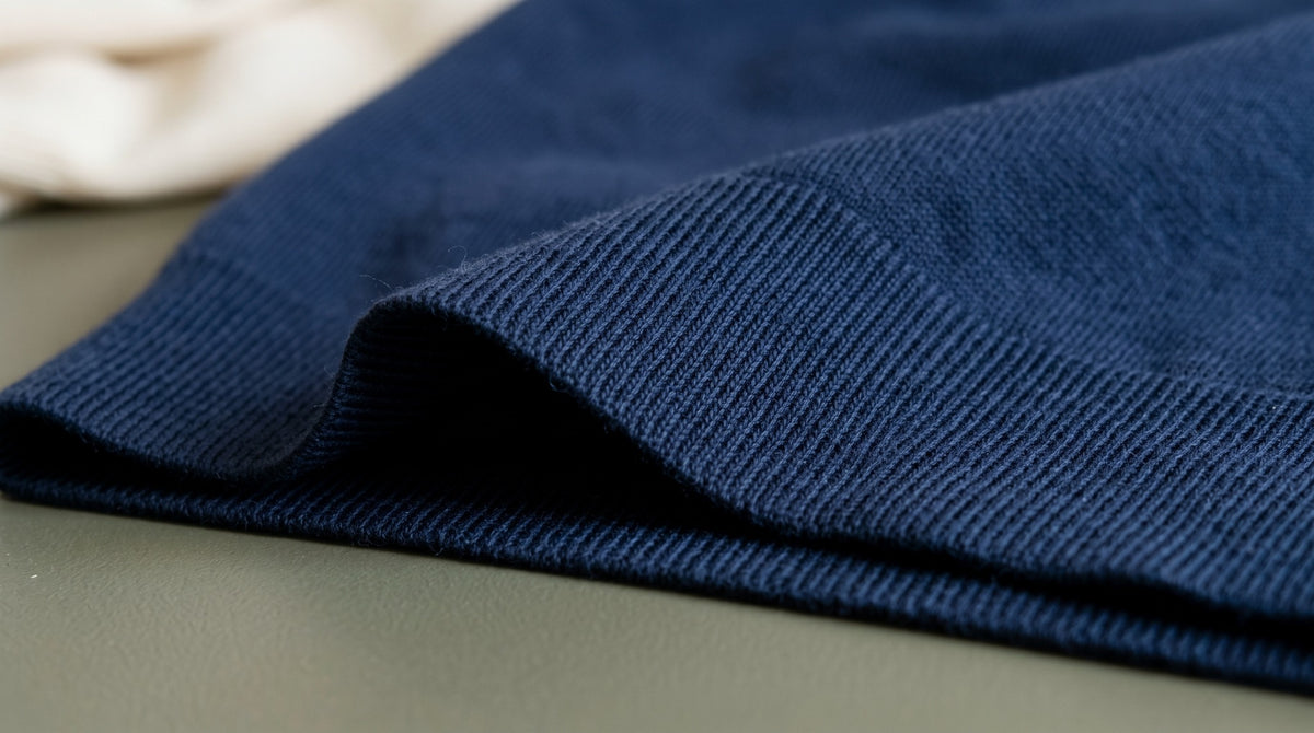 Close view of navy cotton knitting and a folded ribbed hem.