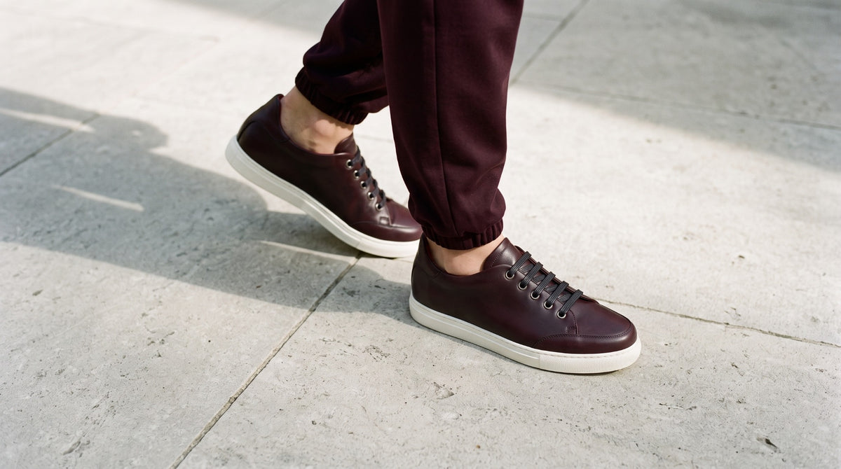 Woman walking in burgundy leather sneakers and matching relaxed joggers.