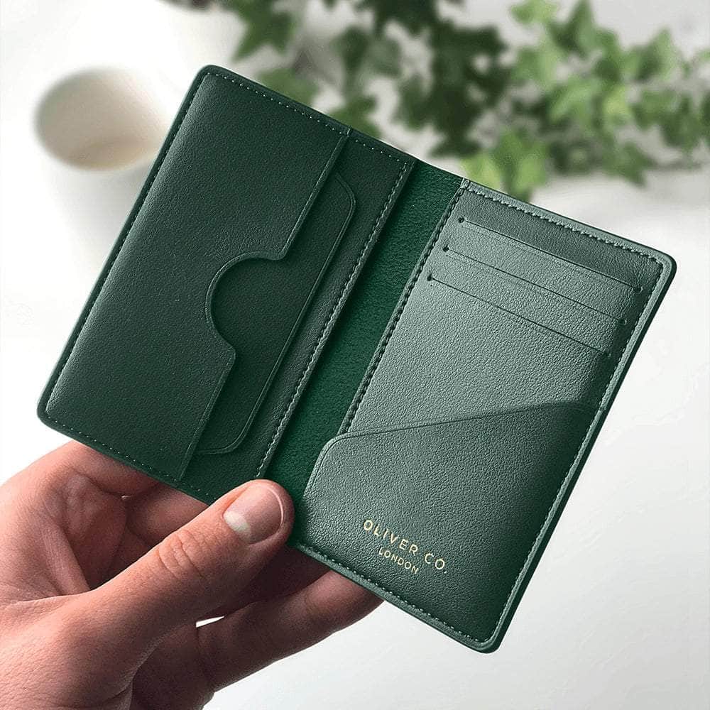 Green vegan leather compact wallet with card slots, held open in hand, minimalist design
