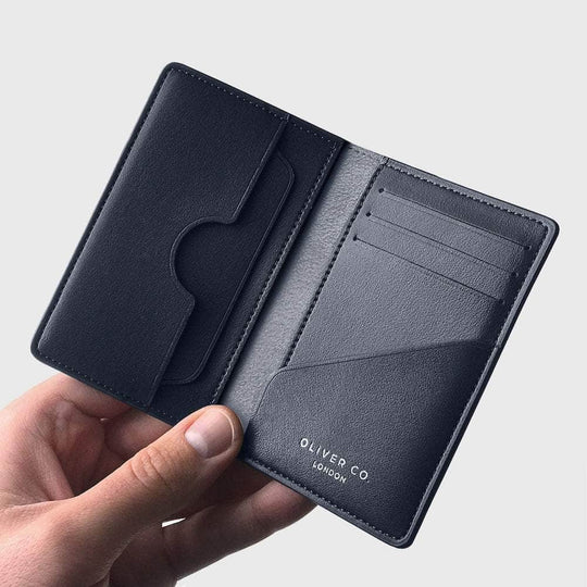 Slim black vegan compact wallet with card slots and pocket, held open in a hand
