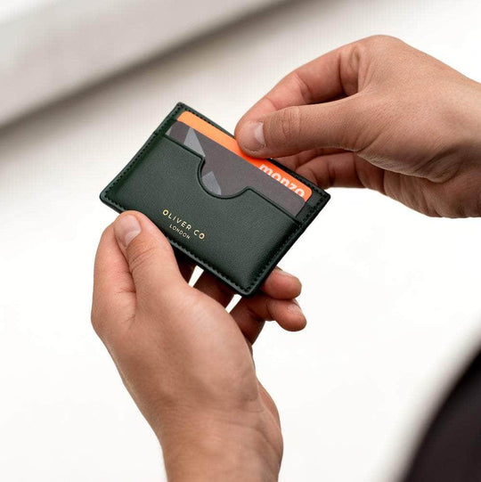 Person holding a slim vegan card holder in dark green with cards inside