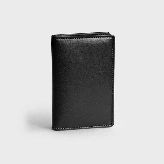 Black vegan leather compact wallet with smooth finish on a light gray background