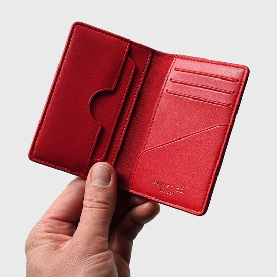 Hand holding an open red vegan compact wallet with card slots and RFID protection