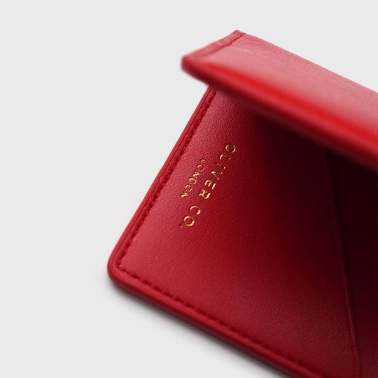 Close-up of a red vegan leather compact wallet with gold embossed text on the inside